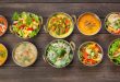 Selection of Indian vegan dishes such as hot spicy indian soups, rice and salads in copper bowls.