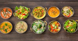 Selection of Indian vegan dishes such as hot spicy indian soups, rice and salads in copper bowls.