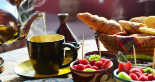 Setting of a traditional Moroccan breakfast with hot mint tea, fruits and baked goods.