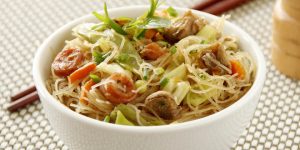 Fried Pancit bihon noodles, one of the best-known filipino foods, served on a bowl with chopstick