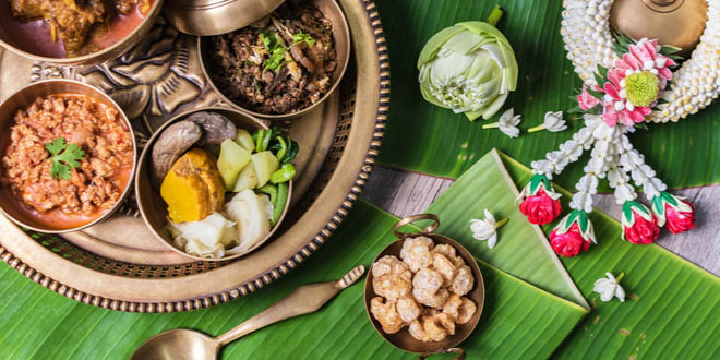 Thai snacks including pork curry, chilli dip, minced pork salad, soft boiled vegetables and pork snack served in brass dishes.