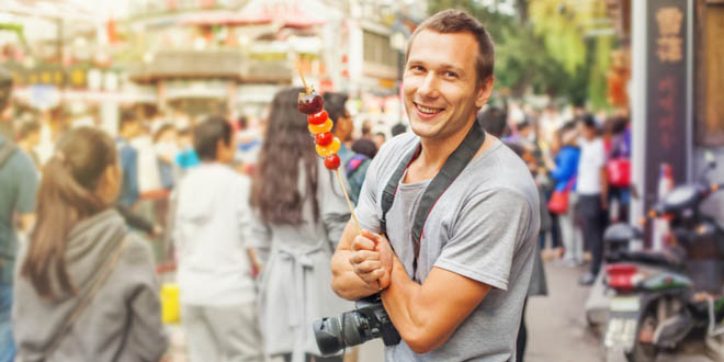 Man posing with a camera for taking amazing food pictures when travelling.