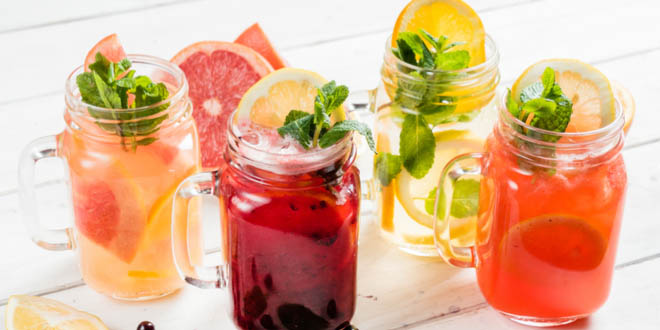 Four rustic glasses with colorful international summer drinks.