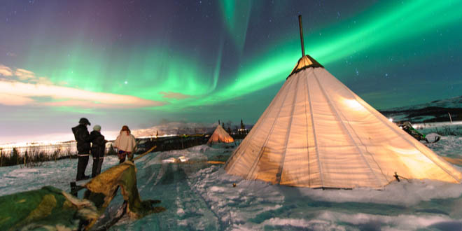 Traditional Sami tents (lappish yurts) in Norway offering tourists a comfortable place to watch the polar lights from after having a drink at an ice bar.