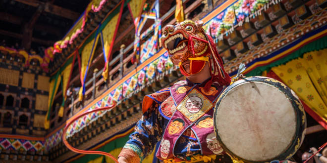 Buddhist monk dancing with a dragon mask at Paro Tsechu festival in Bhutan, a great ocassion for trying typical Bhutanese dishes.