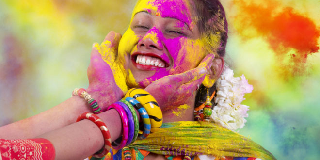 Fun, Food and Festivals in India. Portrait of a young Indian woman celebrating the Holi color festival.