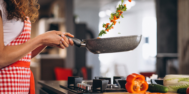 Woman chef cooking vegetables in pan